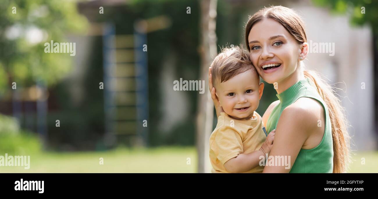 madre eccitato e giovane che tiene in braccio figlio toddler, bandiera Foto Stock