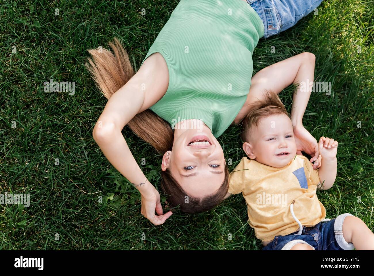 vista dall'alto della mamma felice che passa il tempo con il figlio felice mentre si trova sull'erba Foto Stock
