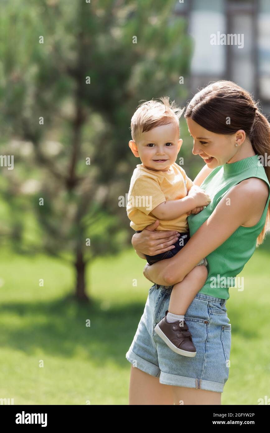 madre gioiosa e giovane che tiene in braccio figlio toddler Foto Stock