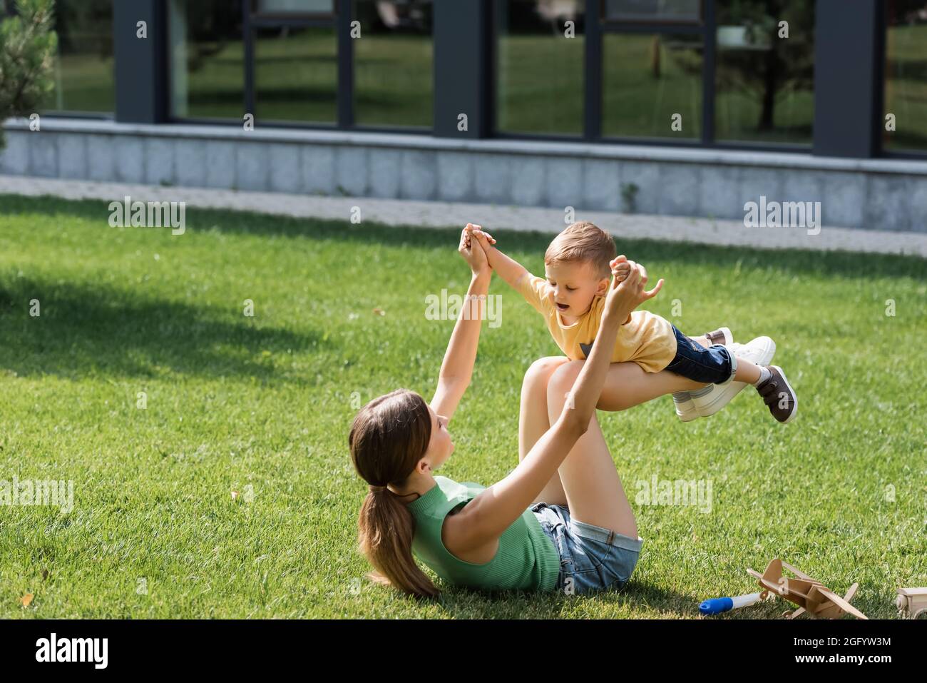 madre sdraiata sull'erba e che solleva il figlio del bambino Foto Stock