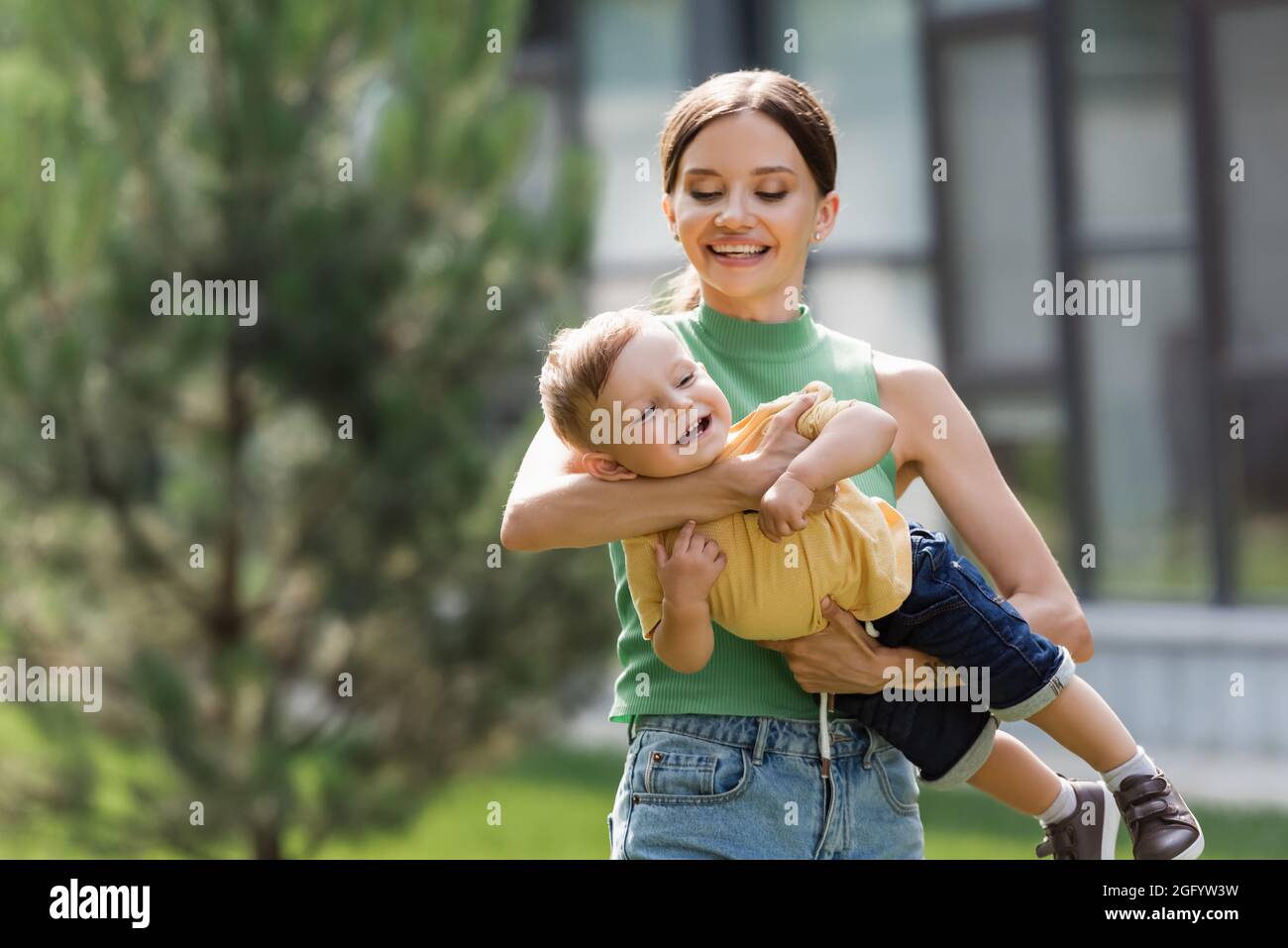 sorridente e giovane madre che tiene in braccio figlio del bambino Foto Stock