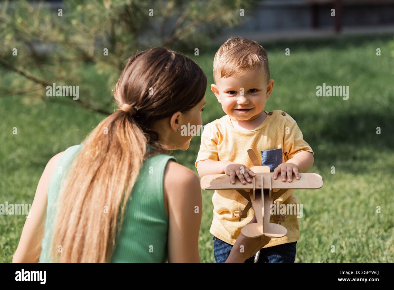 madre che guarda il ragazzo del bambino con il biplano di legno fuori Foto Stock