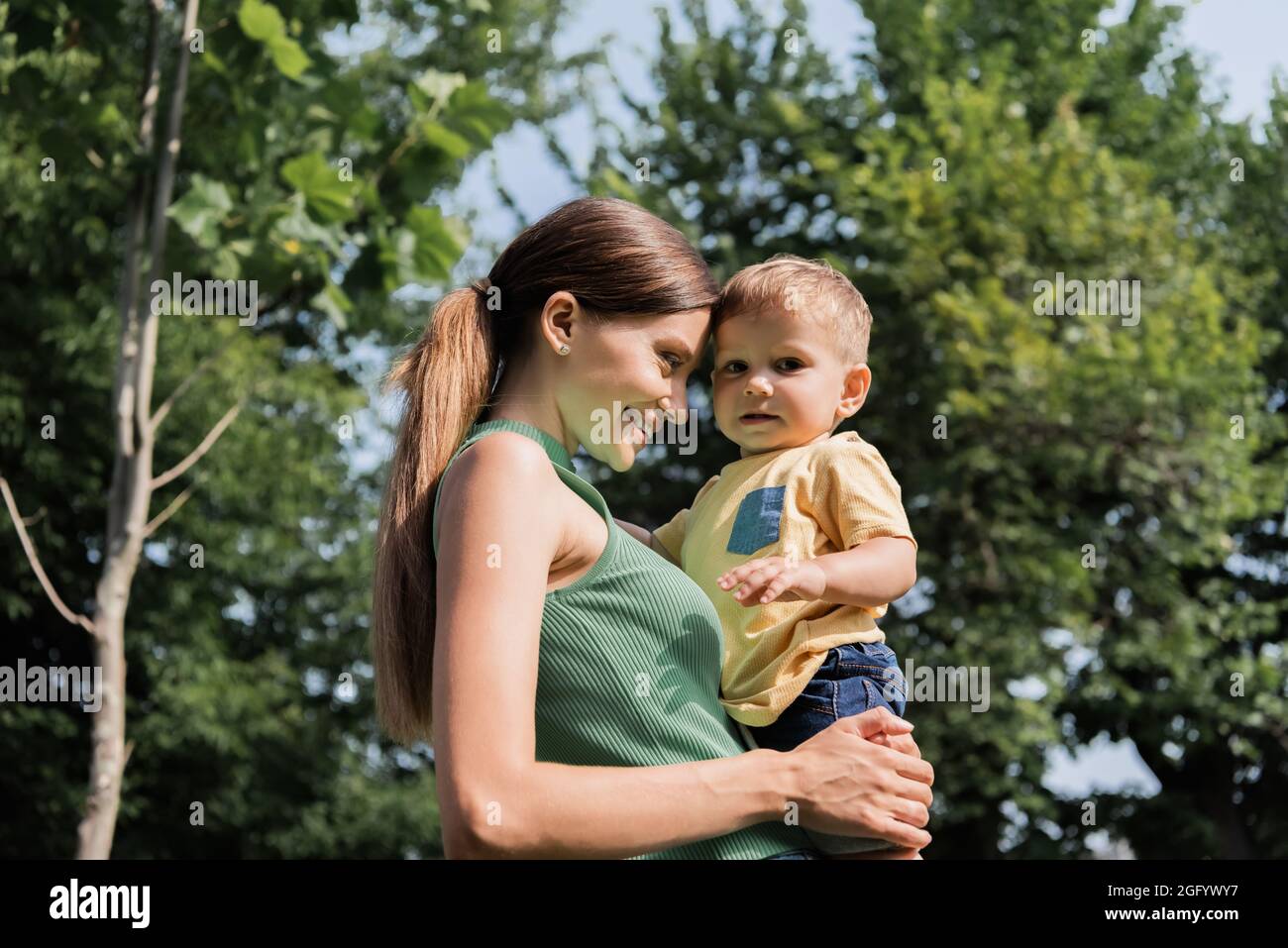 sorridente giovane madre che tiene in braccio simpatico figlio del toddler Foto Stock