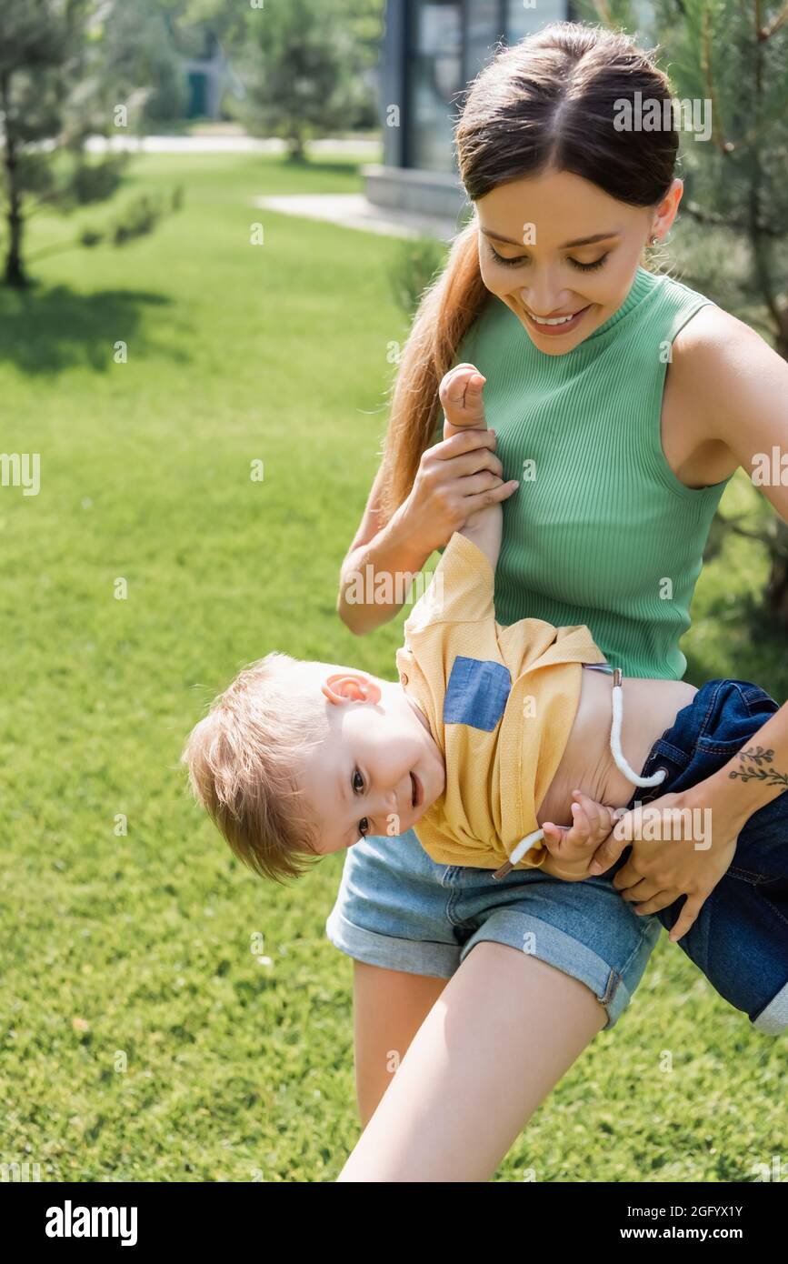 sorridente madre che tiene in braccio felice figlio del bambino fuori Foto Stock