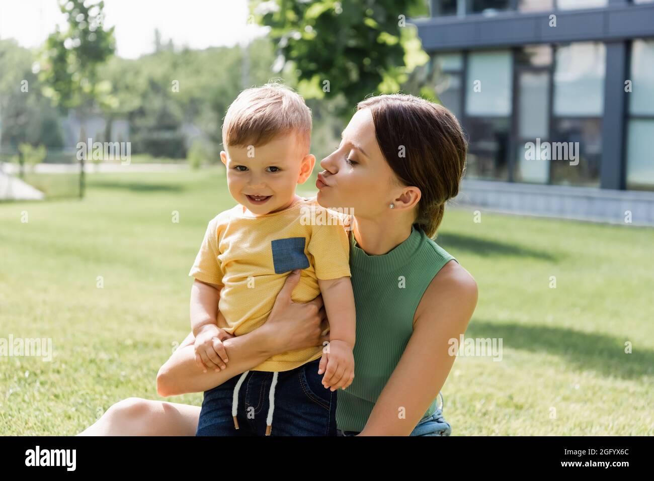 giovane madre baciando felice figlio del bambino fuori Foto Stock