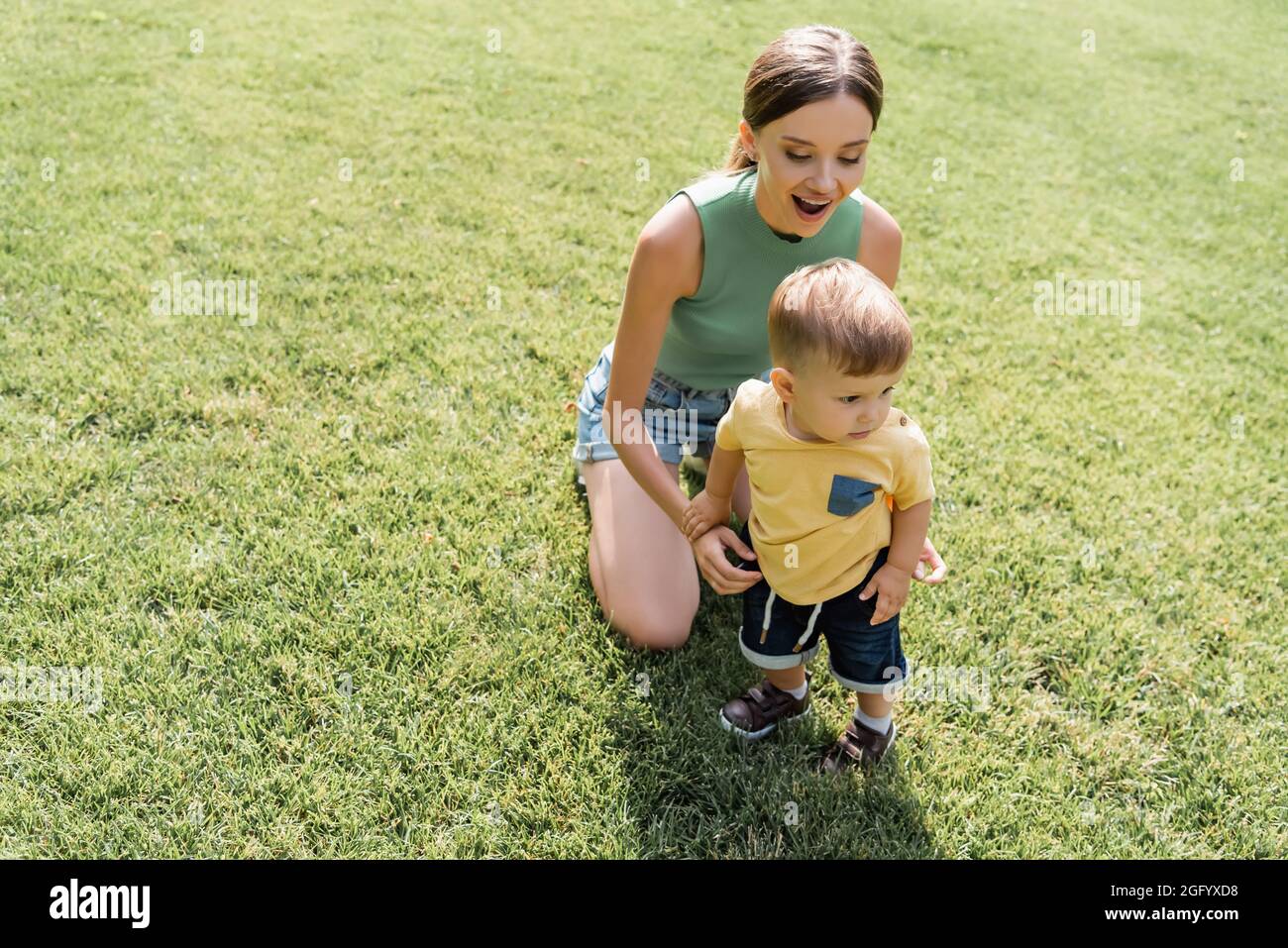la madre stupita che guarda il figlio del bambino in piedi sull'erba verde Foto Stock