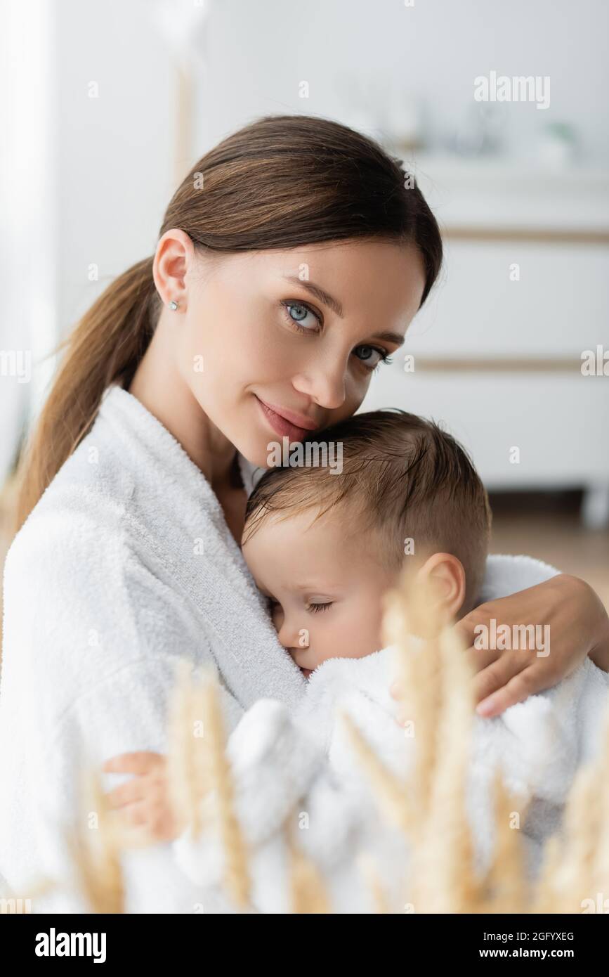 giovane madre che abbraccia il bambino in accappatoio Foto Stock