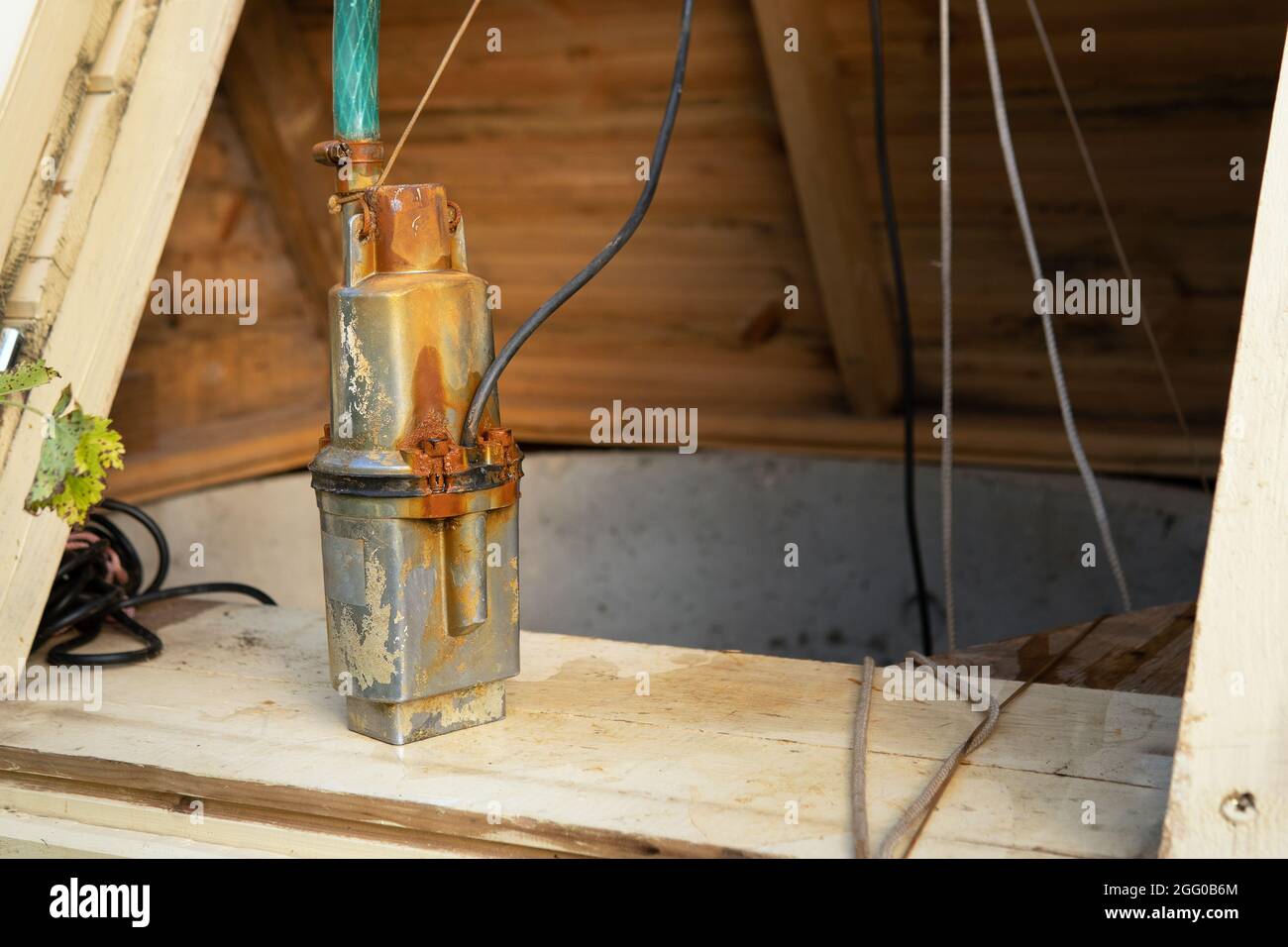 Pompa a pozzetti sommergibili vecchio e arrugginito con un tubo flessibile nel pozzetto Foto Stock