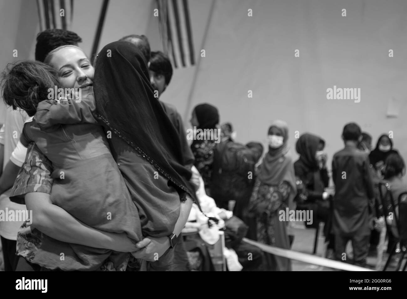 Un soldato centrale dell'esercito degli Stati Uniti accoglie le ragazze afghane evacuate con hugs durante i processi di arrivo a Camp Buehring, Kuwait, 25 agosto 2021. I soldati USARCENT lo hanno colpito rapidamente con i bambini alla struttura, trovando il senso portare sorrisi e risate attraverso il processo. (STATI UNITI Foto dell'esercito di Sgt. Marc Loi) Foto Stock