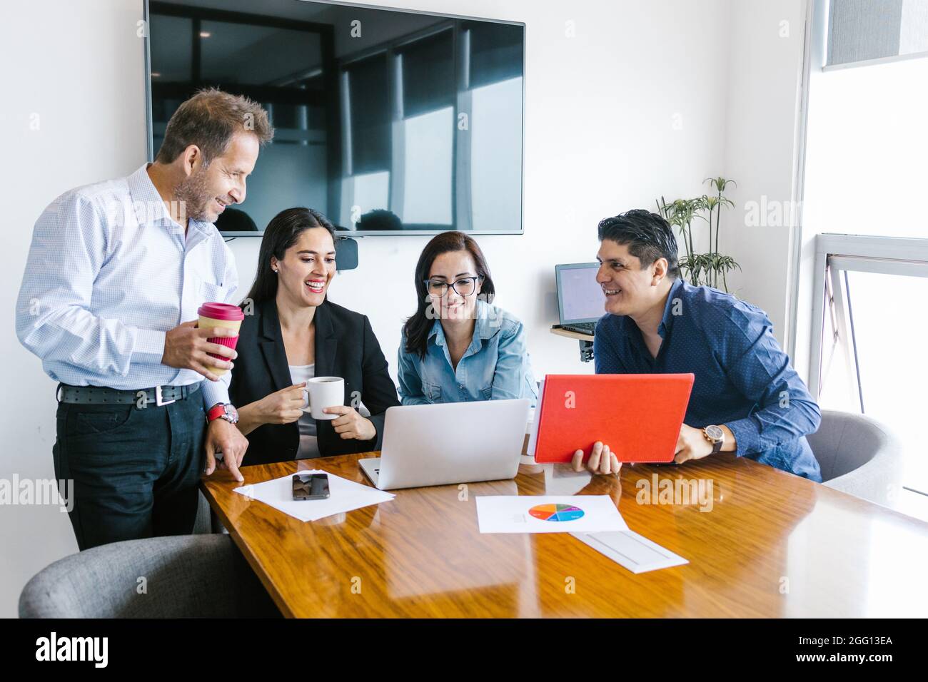 Gruppo di uomini d'affari latini che progettano progetti usando il laptop in un ufficio moderno in Messico Foto Stock