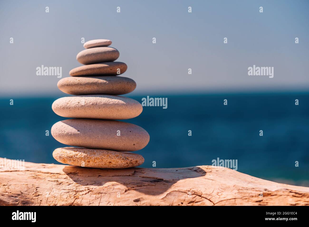 Equilibrata piramide di ciottoli sulla spiaggia in una giornata di sole. Abstract Sea bokeh sullo sfondo. Messa a fuoco selettiva. Pietre Zen sulla spiaggia di mare, meditazione Foto Stock