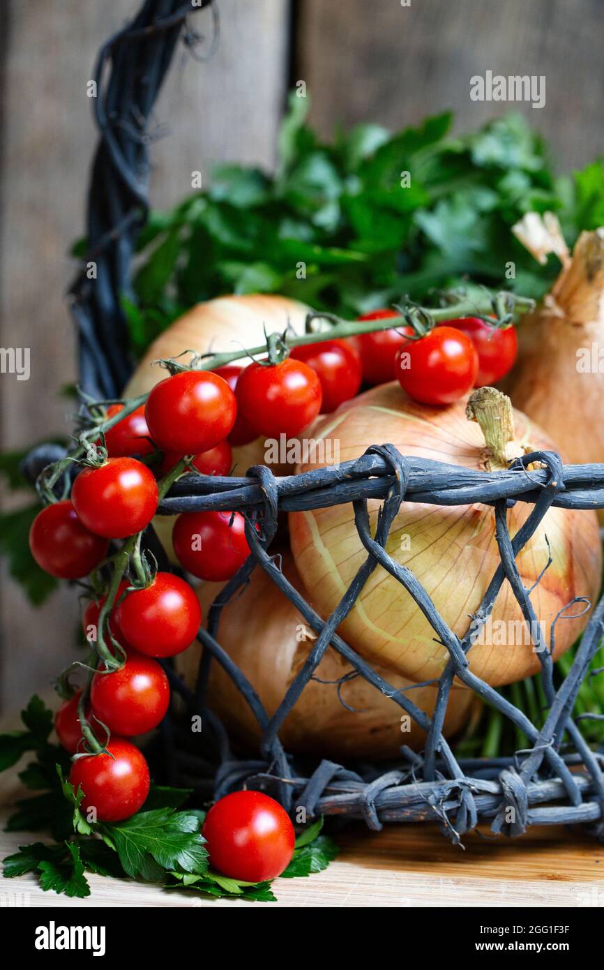 Pomodori ciliegini, cipolle e prezzemolo in un cestino Foto Stock