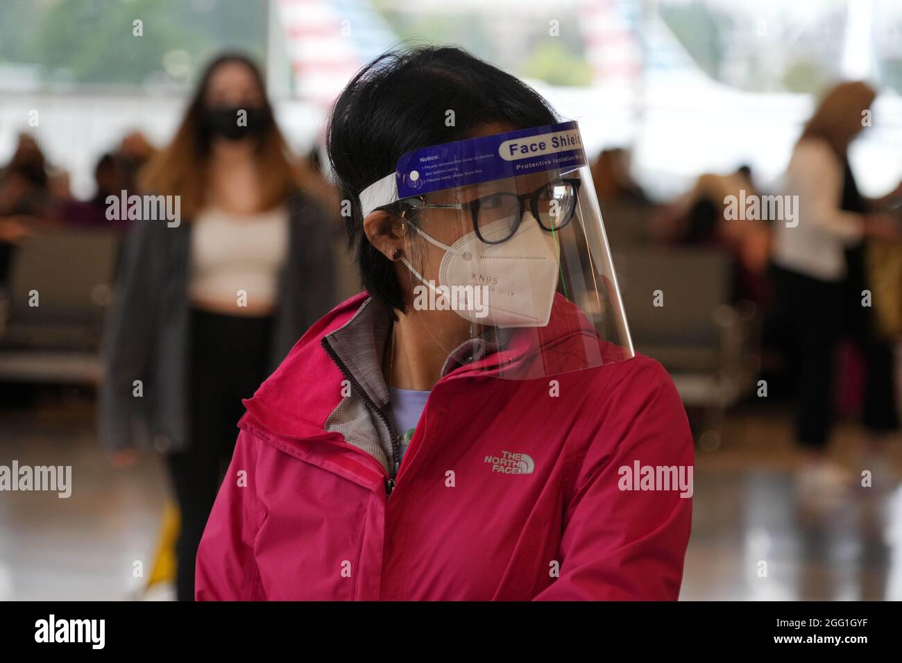 Una donna con maschera facciale e scudo al Terminal Nord dell'Aeroporto Internazionale Seattle-Tacoma, Venerdì, 20 Agosto 2021, a Seattle. Foto Stock