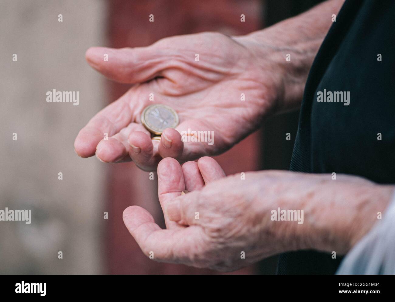 Primo piano le mani stropicciate di una donna anziana contando le monete rimaste in mano Foto Stock