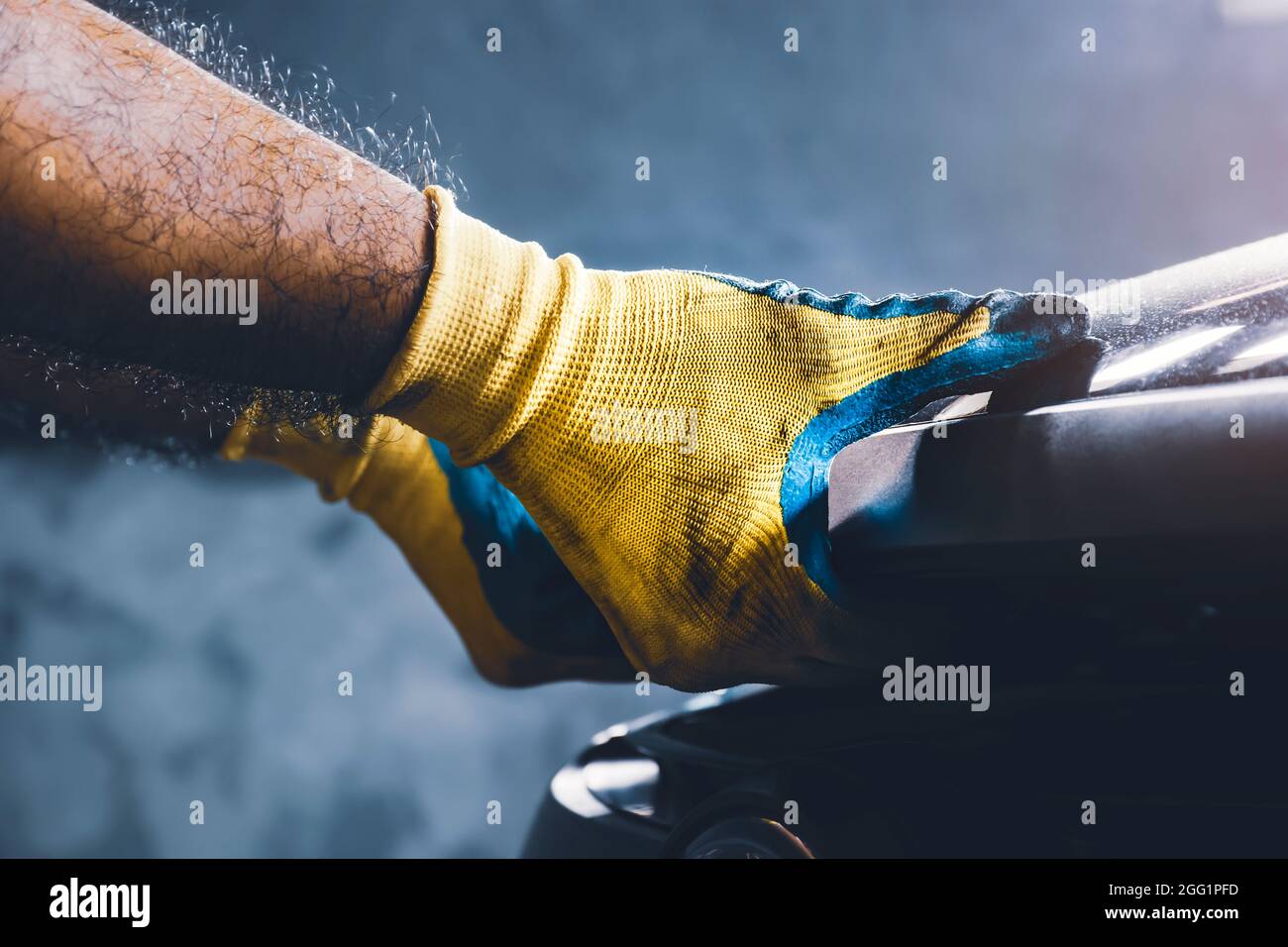 Mano del tecnico che tira verso l'alto il cofano dell'automobile per la manutenzione nell'officina di riparazione Foto Stock