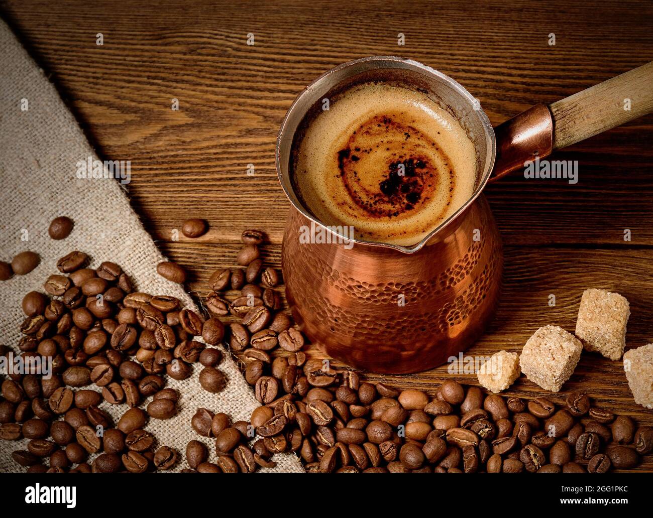 Turk con caffè appena fatto su sfondo di legno Foto Stock