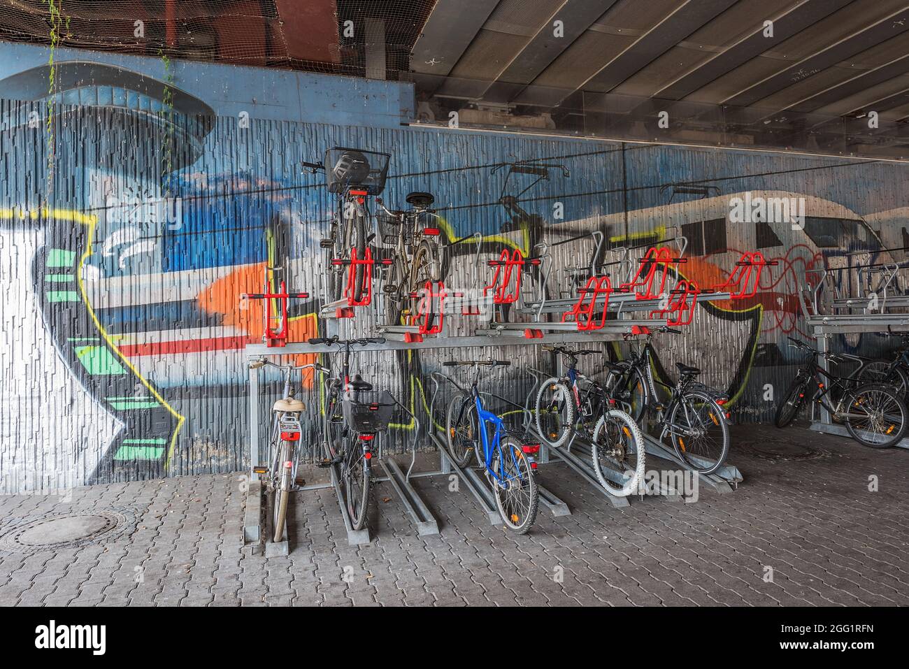 Biciclette sul supporto per biciclette di fronte a una parete di graffiti Foto Stock