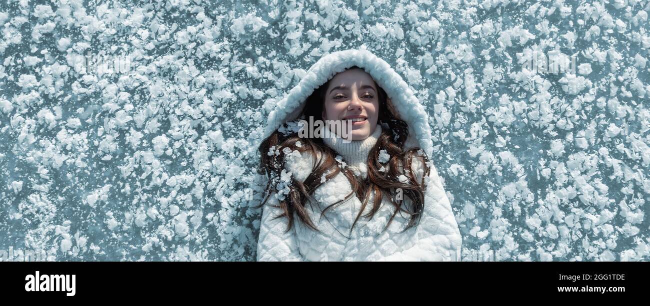 ritratto panoramico di bella, giovane, carina, donna bruna, gelido nel freddo inverno in cappotto bianco e cappuccio, sdraiato surreale come in piedi sul f Foto Stock