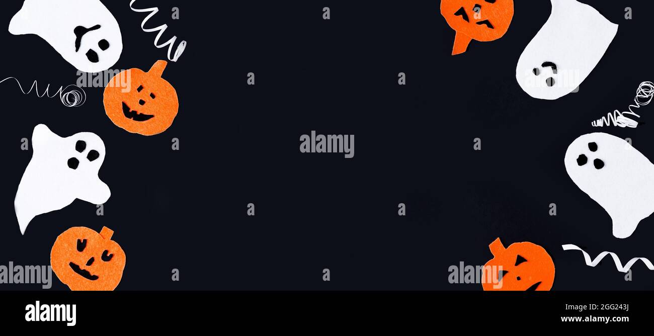 Sfondo di Halloween. Divertenti fantasmi bianchi e zucche in feltro arancione giacciono su uno sfondo nero, spazio di copia, layout piatto, banner Foto Stock