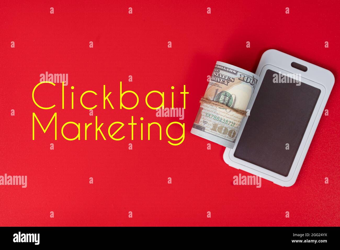 Cellulare replica e un rotolo di falsi soldi con testo Clickbait Marketing. Clickbait è un metodo per indurre l'utente a fare clic su un post in Internet Foto Stock