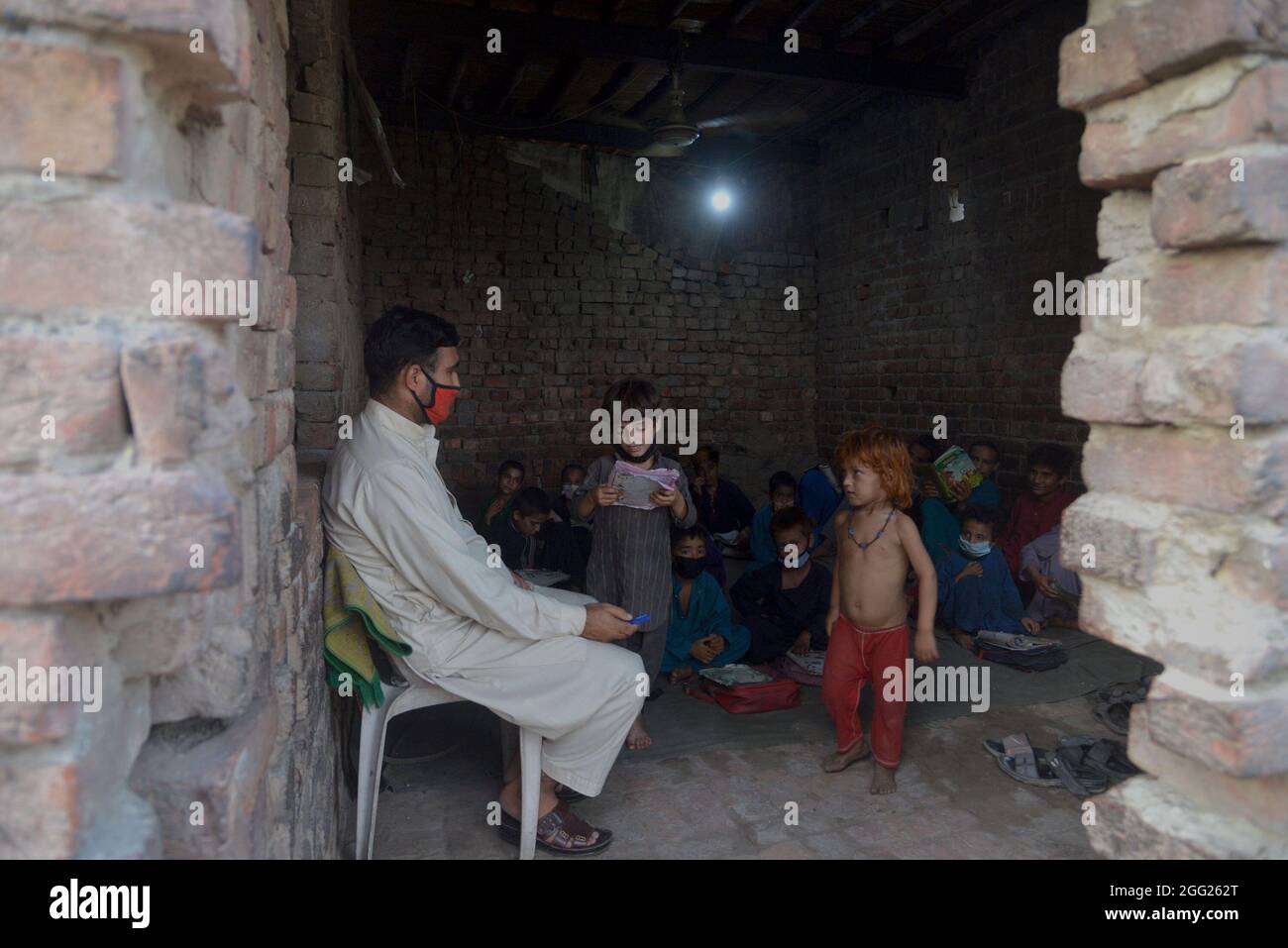 Lahore, Pakistan. 27 ago 2021. Gli studenti afghani che migrano dall'Afghanistan ricevono un'istruzione gratuita da un insegnante volontario amministrato in una sala dilapidata del basti afghano (campo profughi) a Lahore. Un insegnante volontario sta dando l'istruzione libera portando i libri per gli allievi dalla sua tasca. (Foto di Rana Sajid Hussain/Pacific Press) Credit: Pacific Press Media Production Corp./Alamy Live News Foto Stock