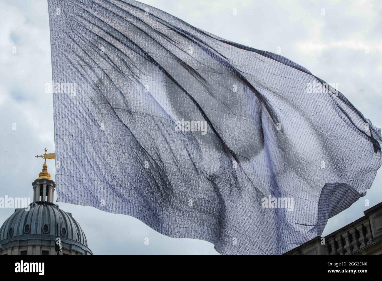 Londra UK 28 agosto 2021 nell'ambito del Greenwich & Docklands International Festival Dan Acher's We are watching, è un'immagine impressionante di un occhio gigante volato su una bandiera monumentale, che comprende migliaia di ritratti digitali, Contributo di persone provenienti da 190 paesi di tutto il mondo.la bandiera di alto livello a 10 piani è stata progettata per inviare un messaggio chiaro ai leader mondiali con il potere di influenzare le decisioni sul cambiamento climatico: Che gli occhi del mondo sono su di loro. Stiamo guardando volerà sopra Greenwich dal 27 al 30 agosto, in anticipo rispetto al COP26 previsto nel corso di quest'anno a Glasgow.Paul Quezada-Neiman/Alamy L Foto Stock