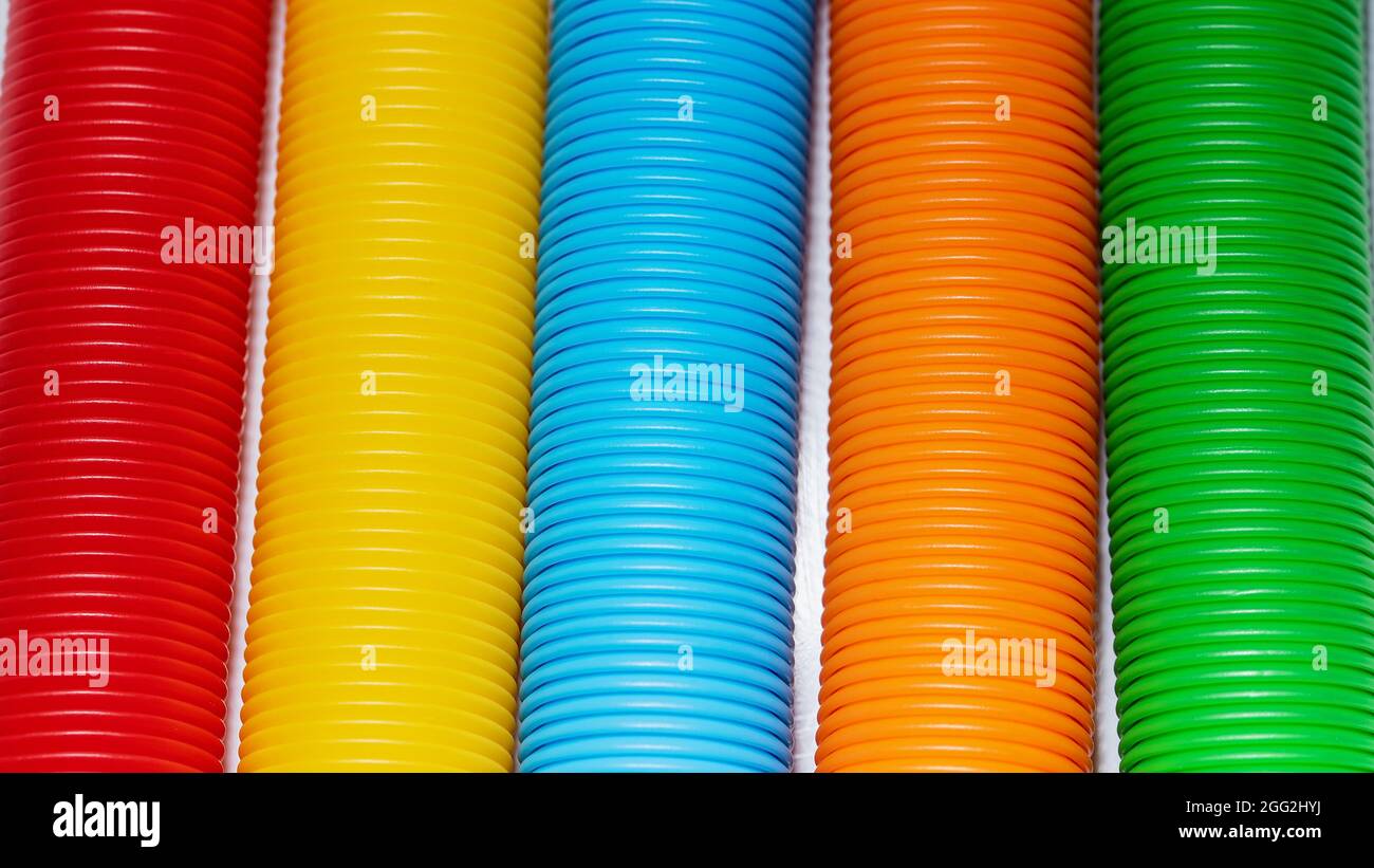 Primo piano della texture di sfondo del colore del giocattolo del tubo pop. Rainbow colori. Fidget push pop anti-stress sensoriale giocattolo. Speciale autismo Foto Stock