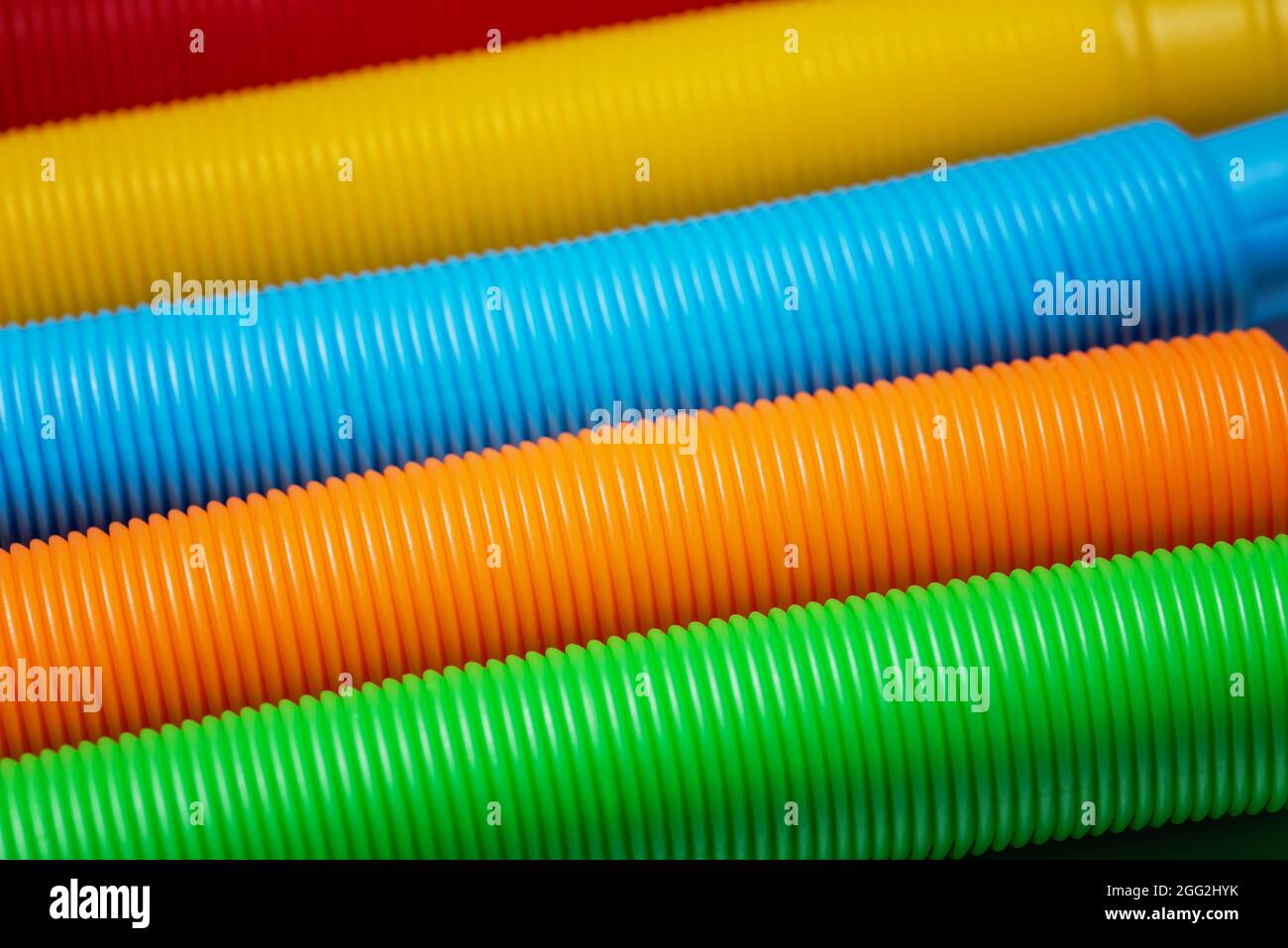 Primo piano della texture di sfondo del colore del giocattolo del tubo pop. Rainbow colori. Fidget push pop anti-stress sensoriale giocattolo. Speciale autismo Foto Stock