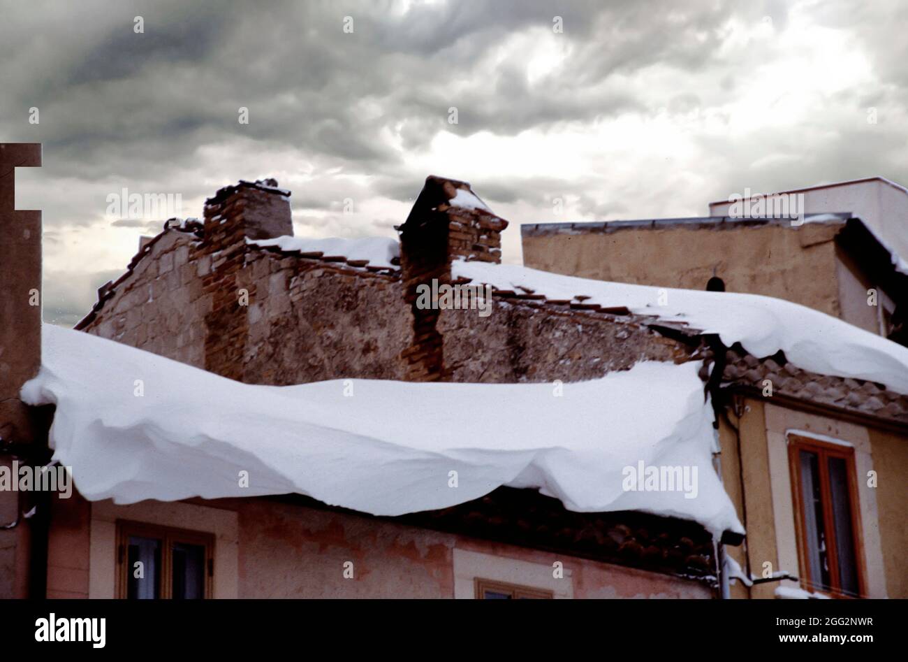 Primo piano di neve accumulata sul bordo di un tetto, nel centro del borgo appenninico, Italia Foto Stock