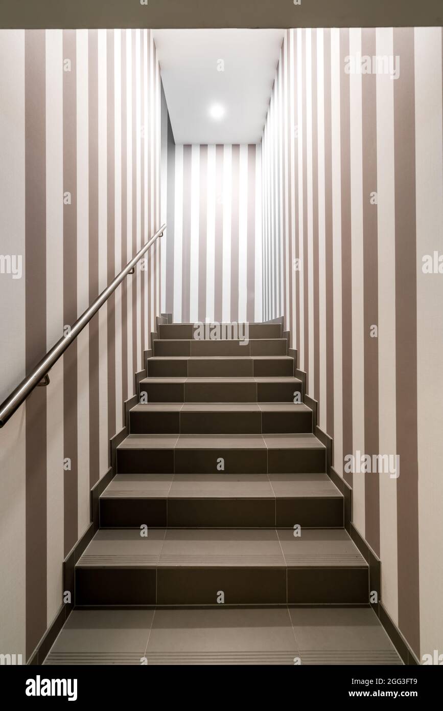 Scatto verticale di scala luminosa e cupa con strisce verticali scure e bianche sulle pareti. Concetto di labirinto, labirinto, mistero, camera segreta. Foto Stock