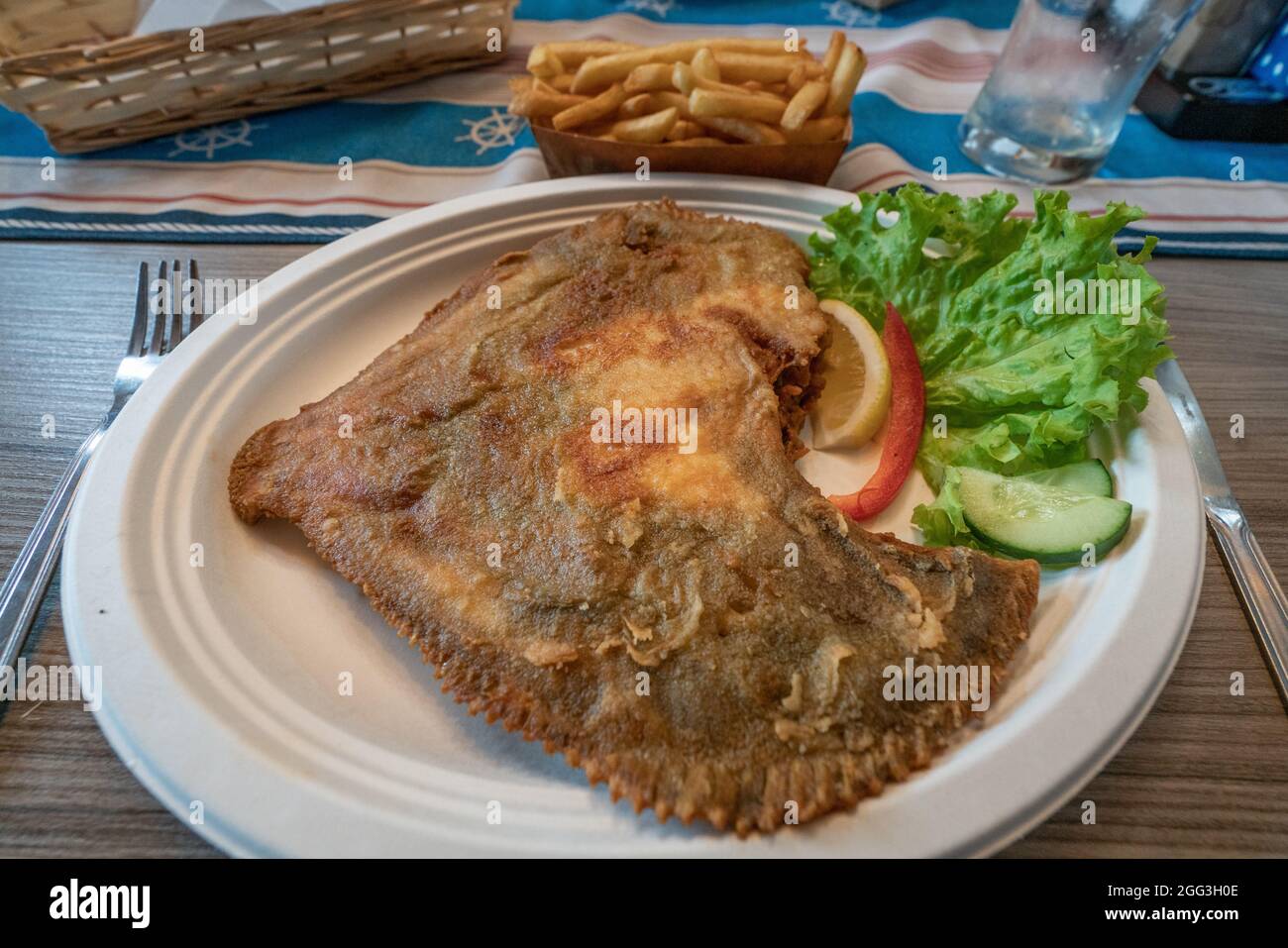 Primo piano di rombo fritto su un piatto bianco nel pub locale di Hel, Polonia. Cucina tradizionale polacca di mare. Foto Stock