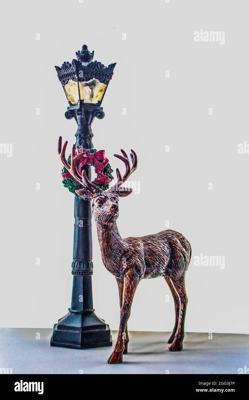 Statuetta del cervo in piedi dal lampione di Natale retrò con la corona di fronte a sfondo bianco - stanza per la copia. Foto Stock