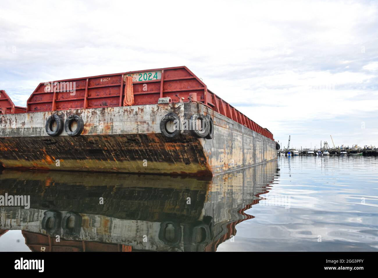 Chiatta di sabbia e ghiaia legata al molo di un porto funzionante. Long Island, New York. Spazio di copia. Foto Stock