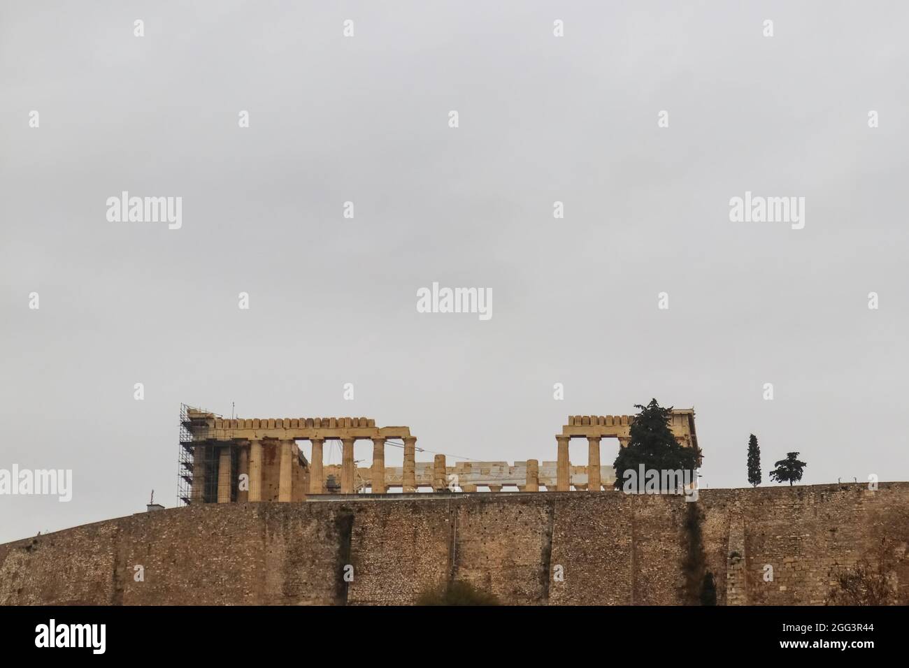 Vista di Partenone sull'Acropoli sopra il muro di contenimento delineato contro un cielo grigio dal Museo dell'Acropoli - Sala per la copia Foto Stock