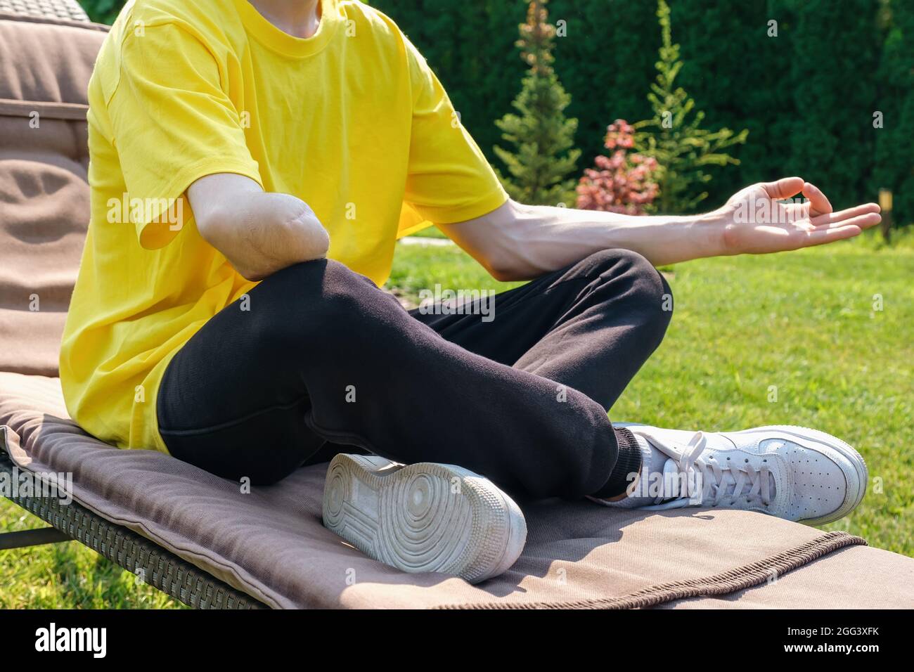 Uomo con braccio amputato che si esercita con elastico in gomma all'esterno Foto Stock