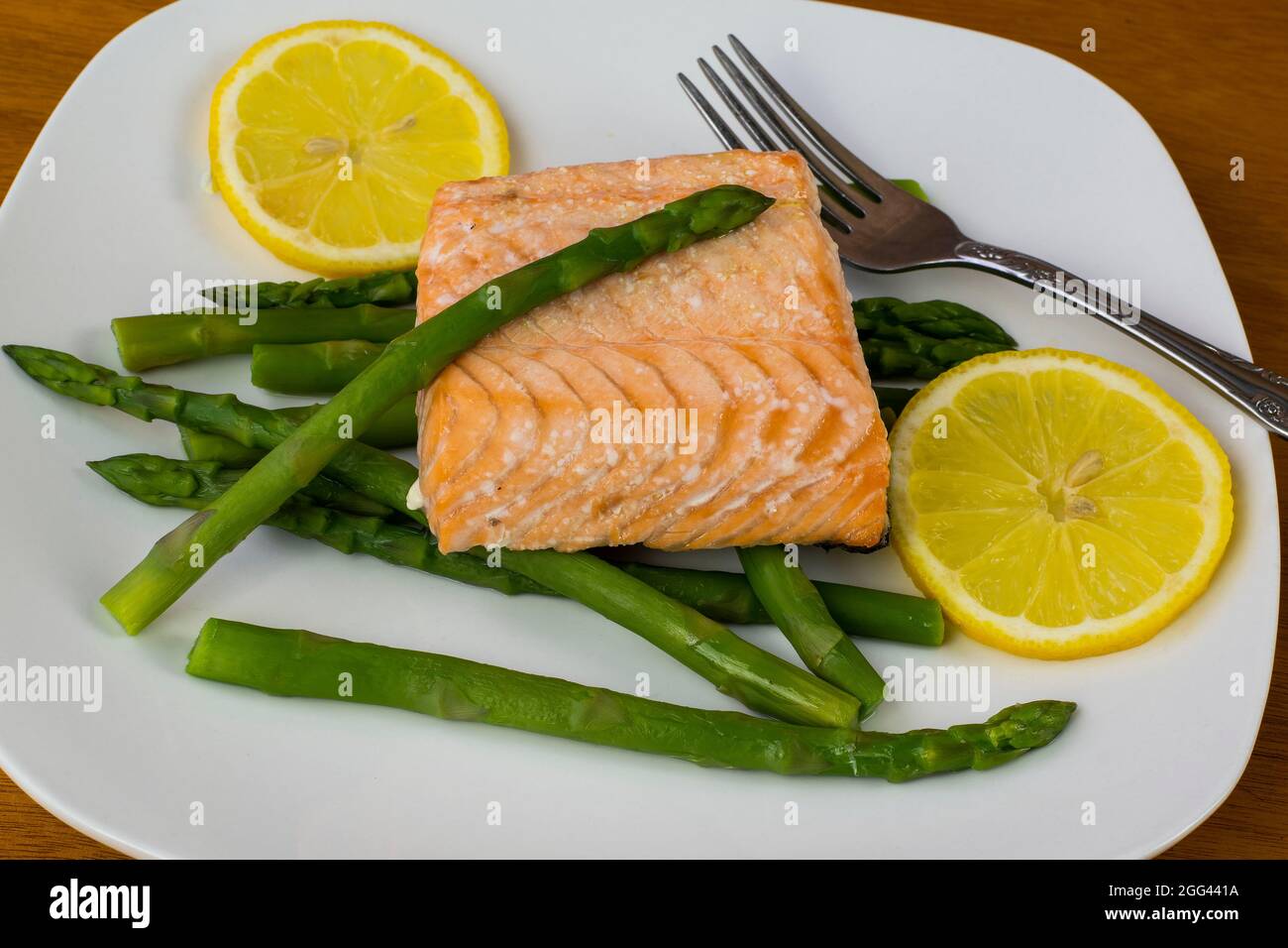 salmone al forno servito con asparagi e limone affettato, Foto Stock