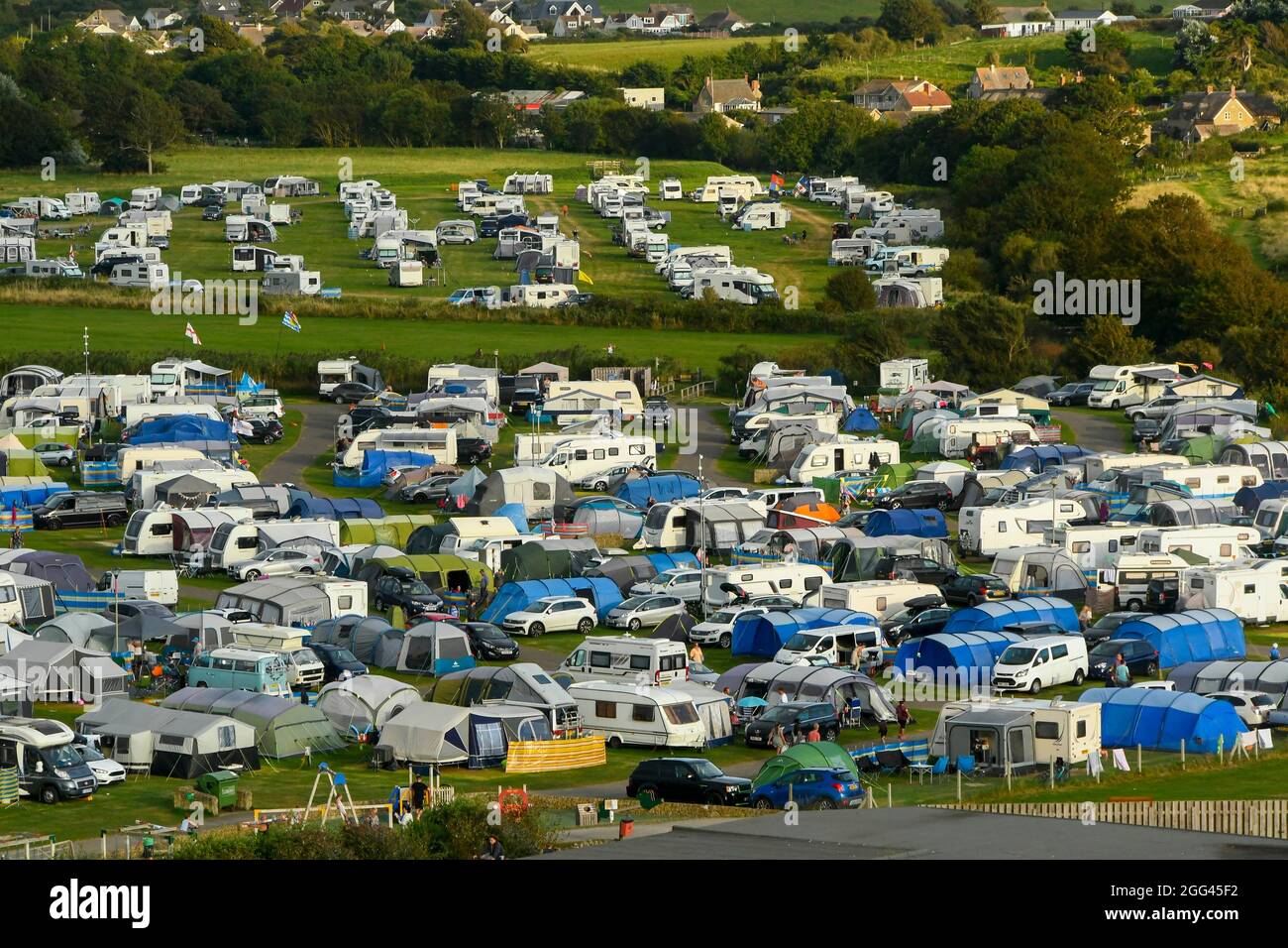 Burton Bradstock, Dorset, Regno Unito. 28 agosto 2021. Meteo Regno Unito. Il campo da campeggio del Freshwater Beach Holiday Park di Burton Bradstock nel Dorset è pieno di roulotte, tende e camper per i turisti in una calda serata di sole durante il fine settimana delle festività. Picture Credit: Graham Hunt/Alamy Live News Foto Stock