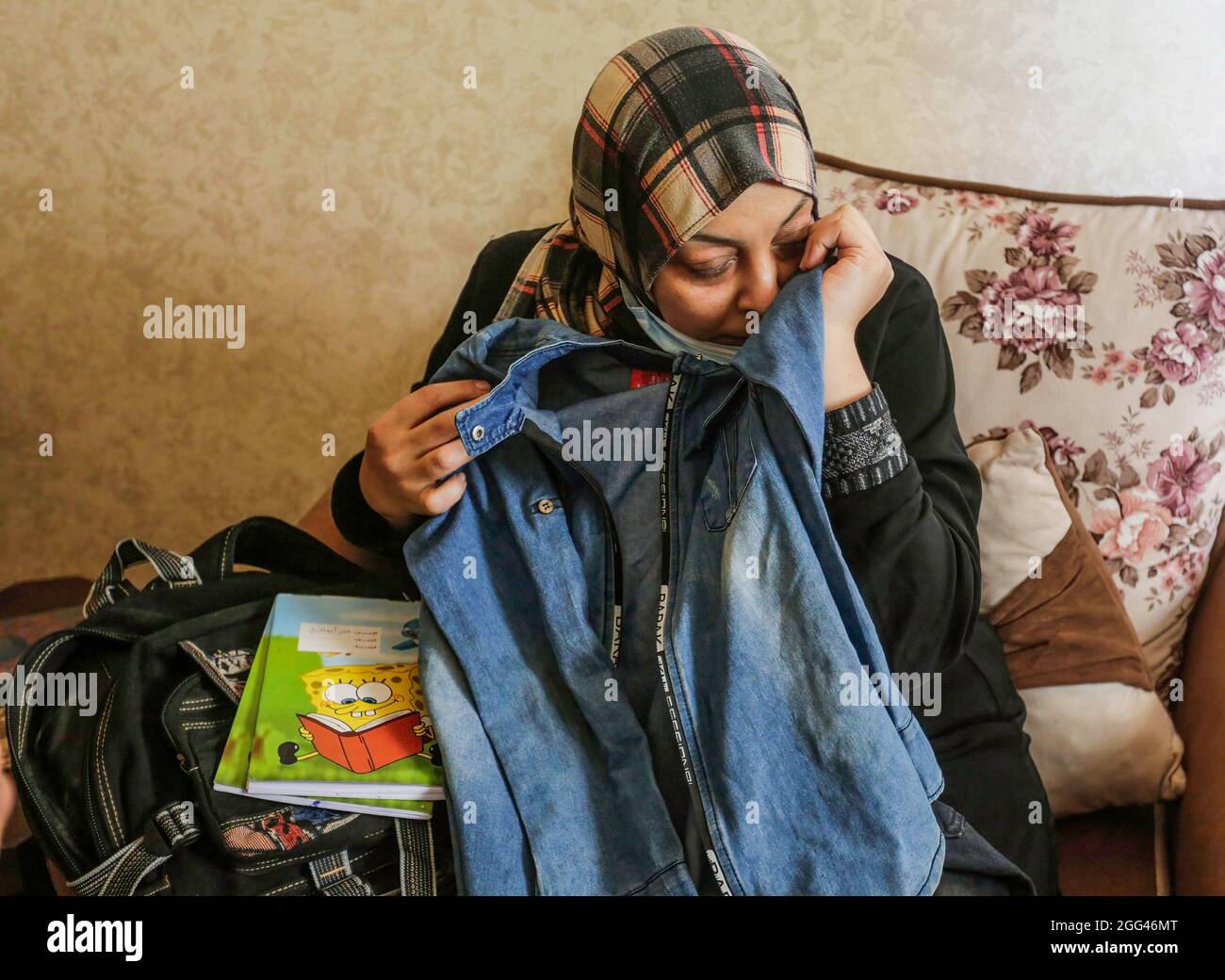 Gaza, Palestina. 28 agosto 2021. Una madre di un teen palestinese Omar Abu Neal mostra la sua scuola, vestiti durante il suo funerale nella città di Gaza. Abu al-Nile è morto di ferite che ha sostenuto durante una protesta contro la recinzione di confine tra Israele e Gaza il 21 agosto 2021. I disordini hanno lasciato 42 manifestanti feriti e cecchino israeliano è stato anche sparato e in una condizione critica. Credit: SOPA Images Limited/Alamy Live News Foto Stock