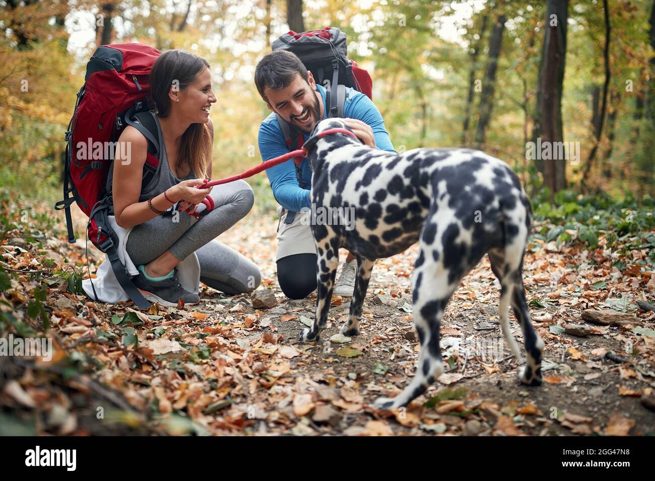 Coppia escursionisti in amore coccolare il loro cane a sentiero escursionistico Foto Stock