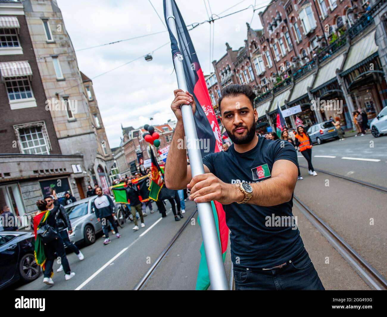 Amsterdam, Paesi Bassi. 28 agosto 2021. Durante la manifestazione, un manifestante detiene una bandiera afghana.migliaia di persone si sono riunite nel centro di Amsterdam per dimostrare il loro sostegno alla popolazione afghana intrappolata a Kabul sotto il regime talebano e per esortare il governo olandese a dichiarare l'Afghanistan un paese di origine non sicuro così come i rifugiati afghani e. Le persone afghane senza documenti possono avere il diritto legale di asilo e sicurezza. (Foto di Ana Fernandez/SOPA Images/Sipa USA) Credit: Sipa USA/Alamy Live News Foto Stock