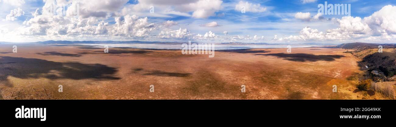 Terreno asciutto e pianeggiante del lago George in NSW, Australia con vento di turbine eoliche di generazione di energia rinnovabile sotto cielo blu nuvoloso - panorama aereo Foto Stock