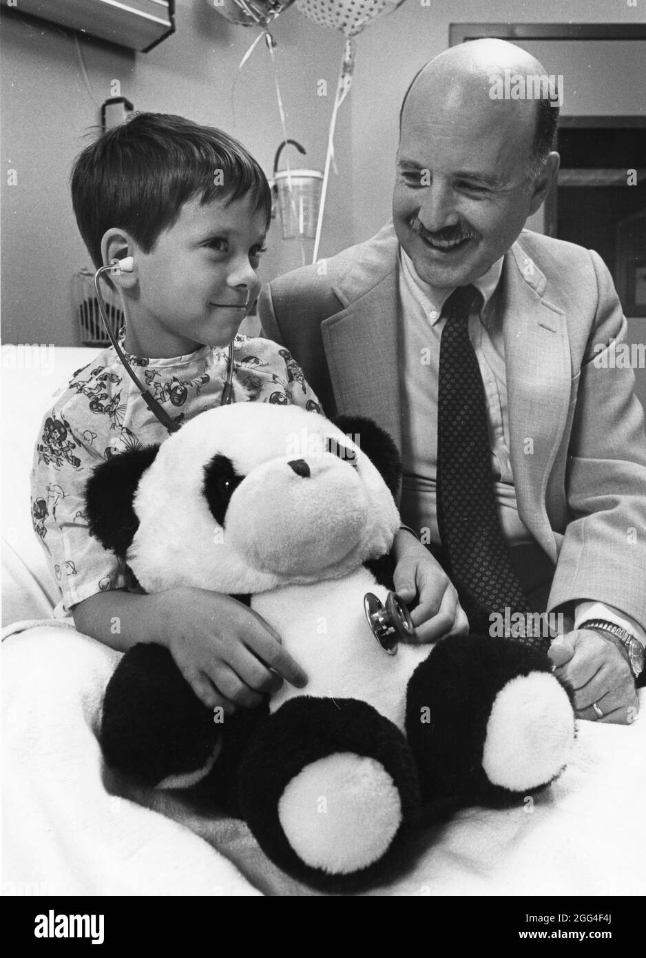 Austin Texas USA, circa 1993: Lo specialista pediatrico permette ai giovani pazienti di usare lo stetoscopio per ascoltare il cuore dell'orso di peluche all'ospedale dei bambini. SIGNOR ©Bob Daemmrich Foto Stock