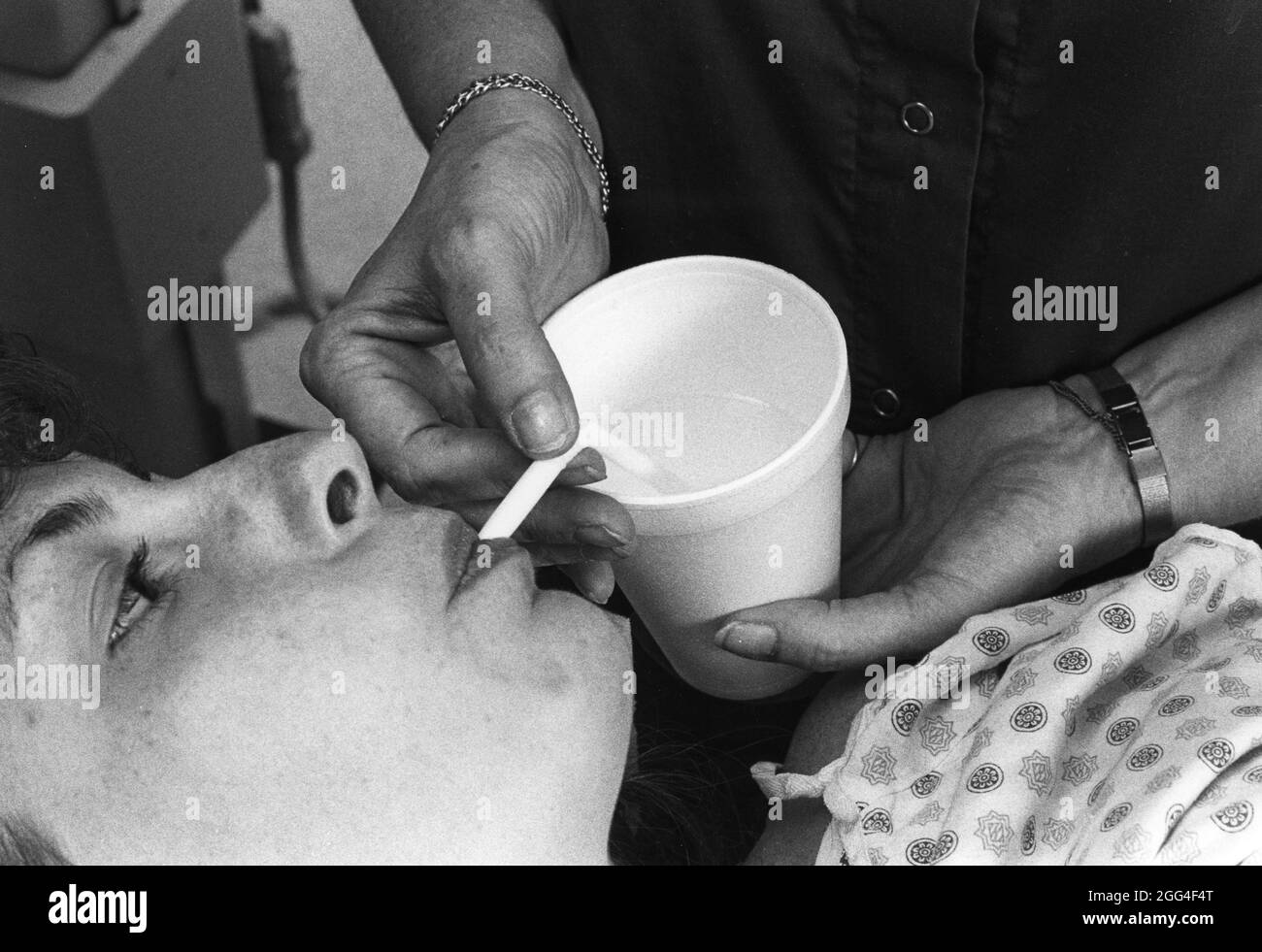 Austin Texas USA, circa 1990: Paziente ospedale femminile beve acqua per lavare i liquidi di prova utilizzati per test medici. ©Bob Daemmrich Foto Stock