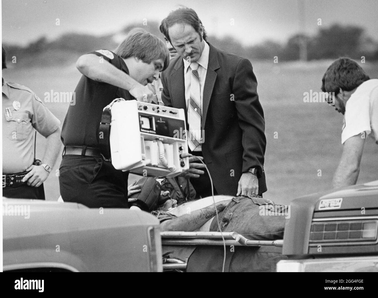 Austin Texas USA, circa 1983: Il tecnico medico di emergenza utilizza una macchina elettrocardiografica portatile EKG per trasmettere i dati all'ospedale in una scena di ripresa per monitorare il paziente. ©Bob Daemmrich Foto Stock