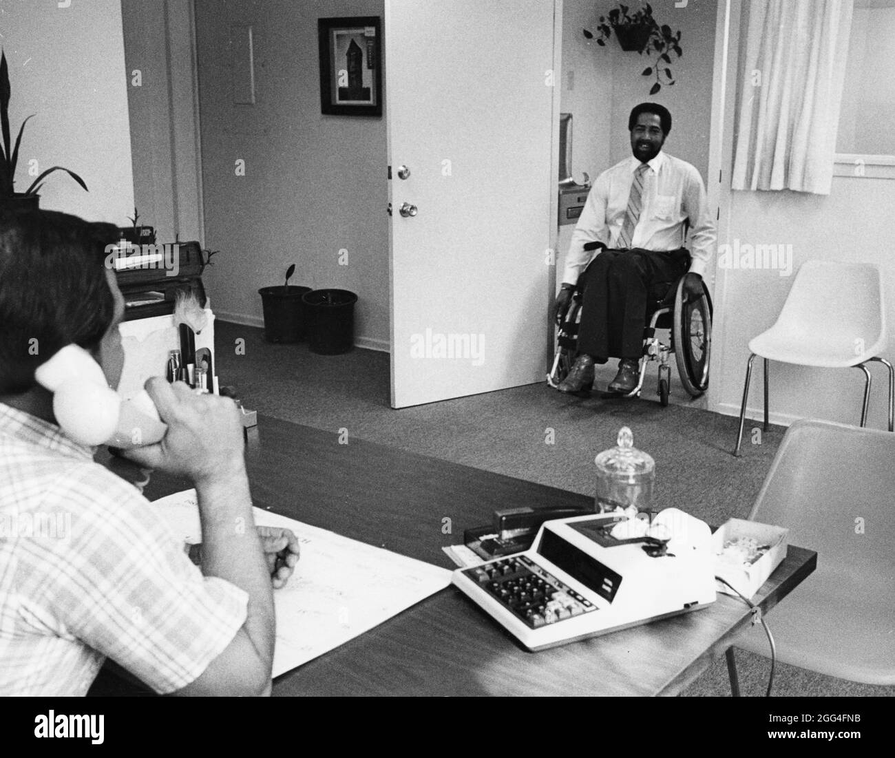 Austin Texas USA, circa 1988: Handicap uomo nero in sedia a rotelle entra in un ufficio per un colloquio di lavoro. ©Bob Daemmrich Foto Stock