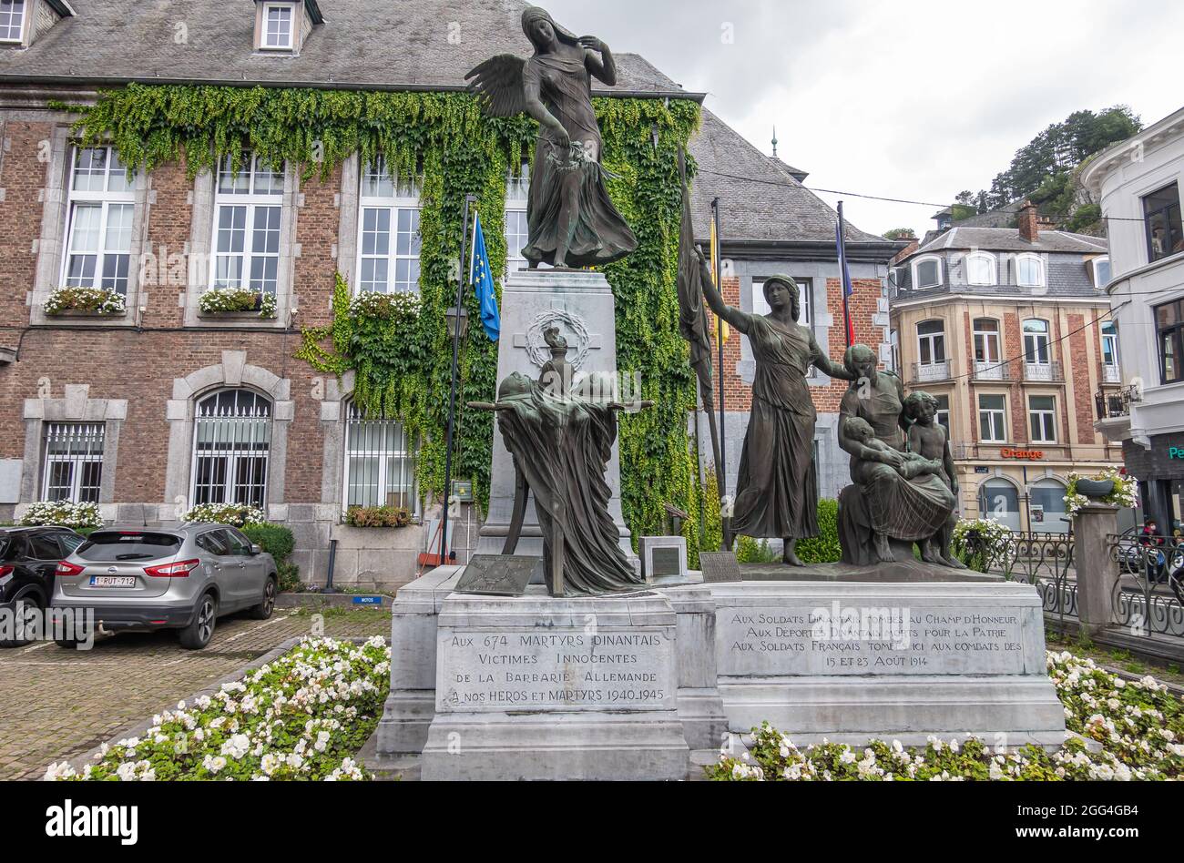 Dinant, Vallonia, Belgio - 8 agosto 2021: In mattoni marroni storici con cornici bianche Municipio, statue di bronzo su piedistallo come monumento alle vittime o Foto Stock