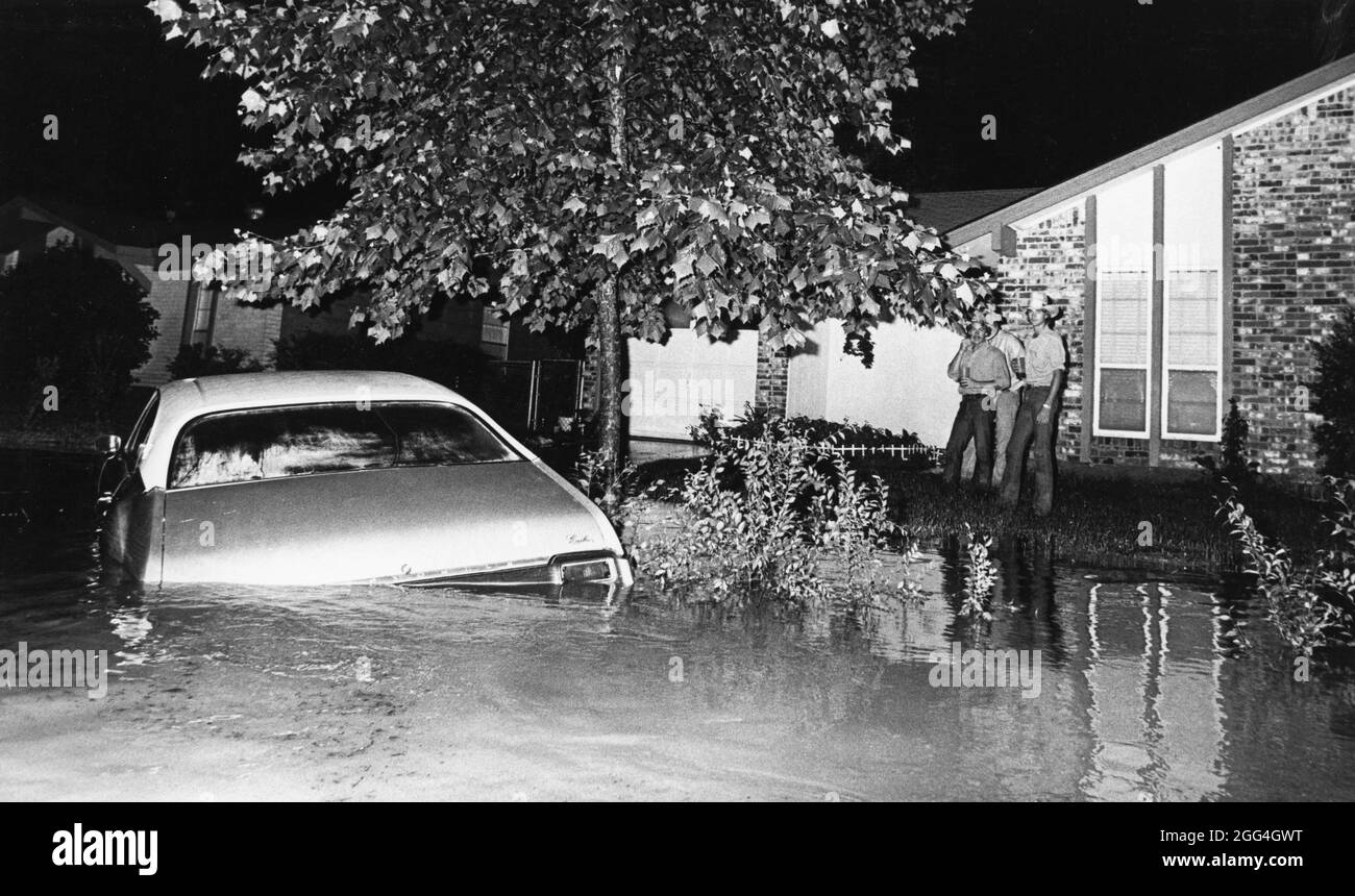 Austin Texas USA,1982: I vicini si trovano su un terreno più alto nel cortile di font mentre guardano la strada inondata e il vialetto durante la notte inondano attraverso il quartiere residenziale vicino a un torrente. ©Bob Daemmrich Foto Stock