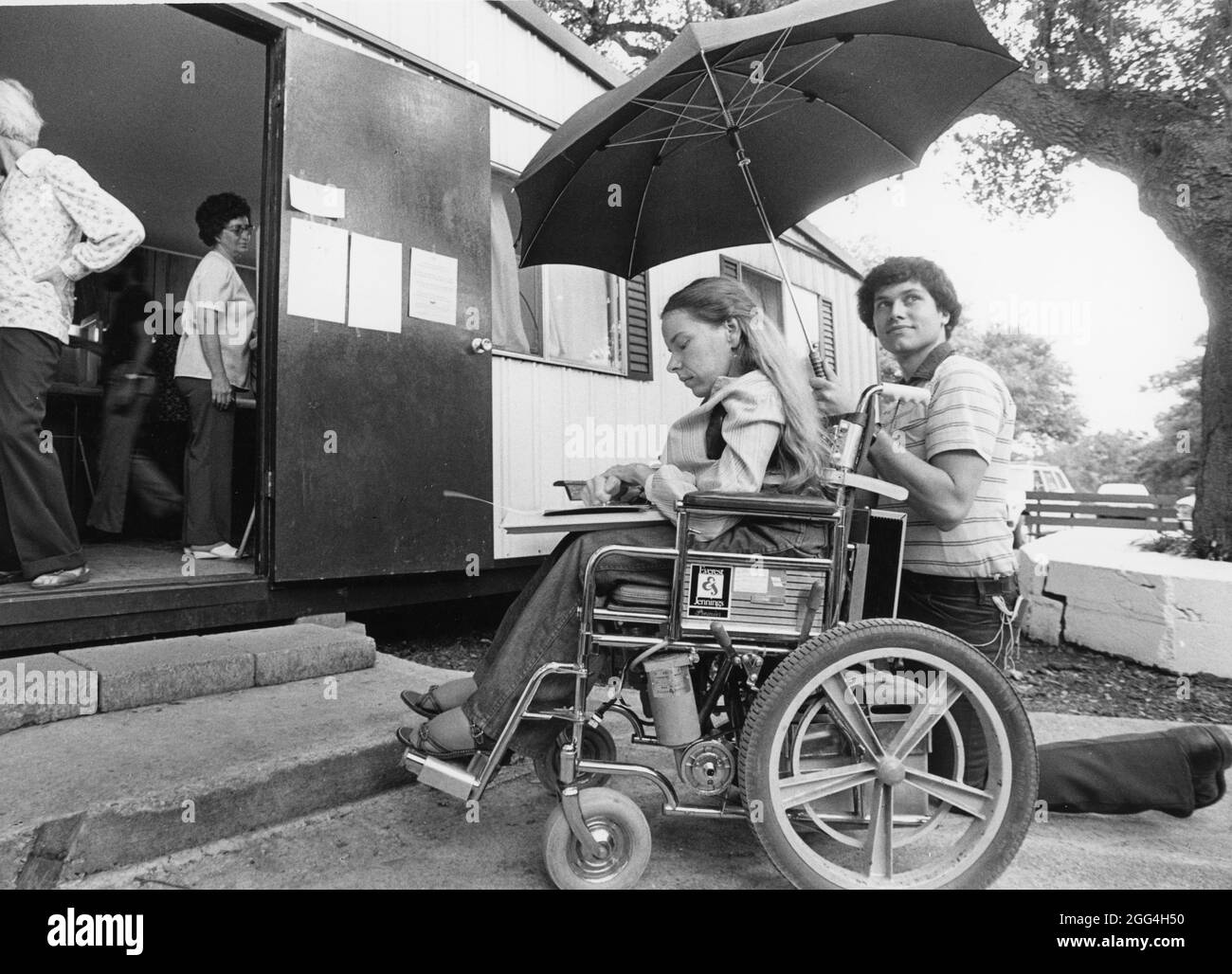 Austin Texas USA,1989: Incapace di accedere al luogo dei sondaggi a causa della mancanza di una rampa, una donna in sedia a rotelle è costretta a votare sotto la pioggia. ©Bob Daemmrich Foto Stock