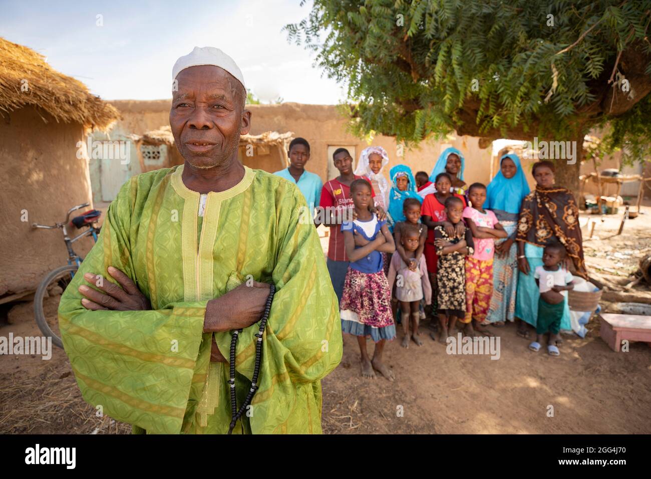 Un uomo si trova fuori casa con mogli e bambini nel loro villaggio nella regione di Ségou, Mali, Africa occidentale. Foto Stock