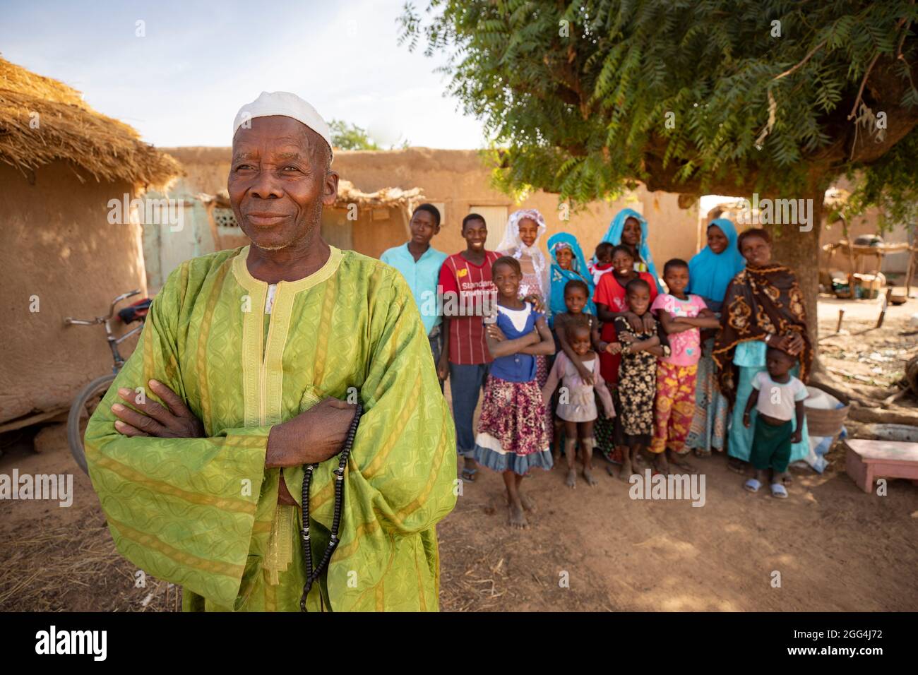 Un uomo si trova fuori casa con mogli e bambini nel loro villaggio nella regione di Ségou, Mali, Africa occidentale. Foto Stock